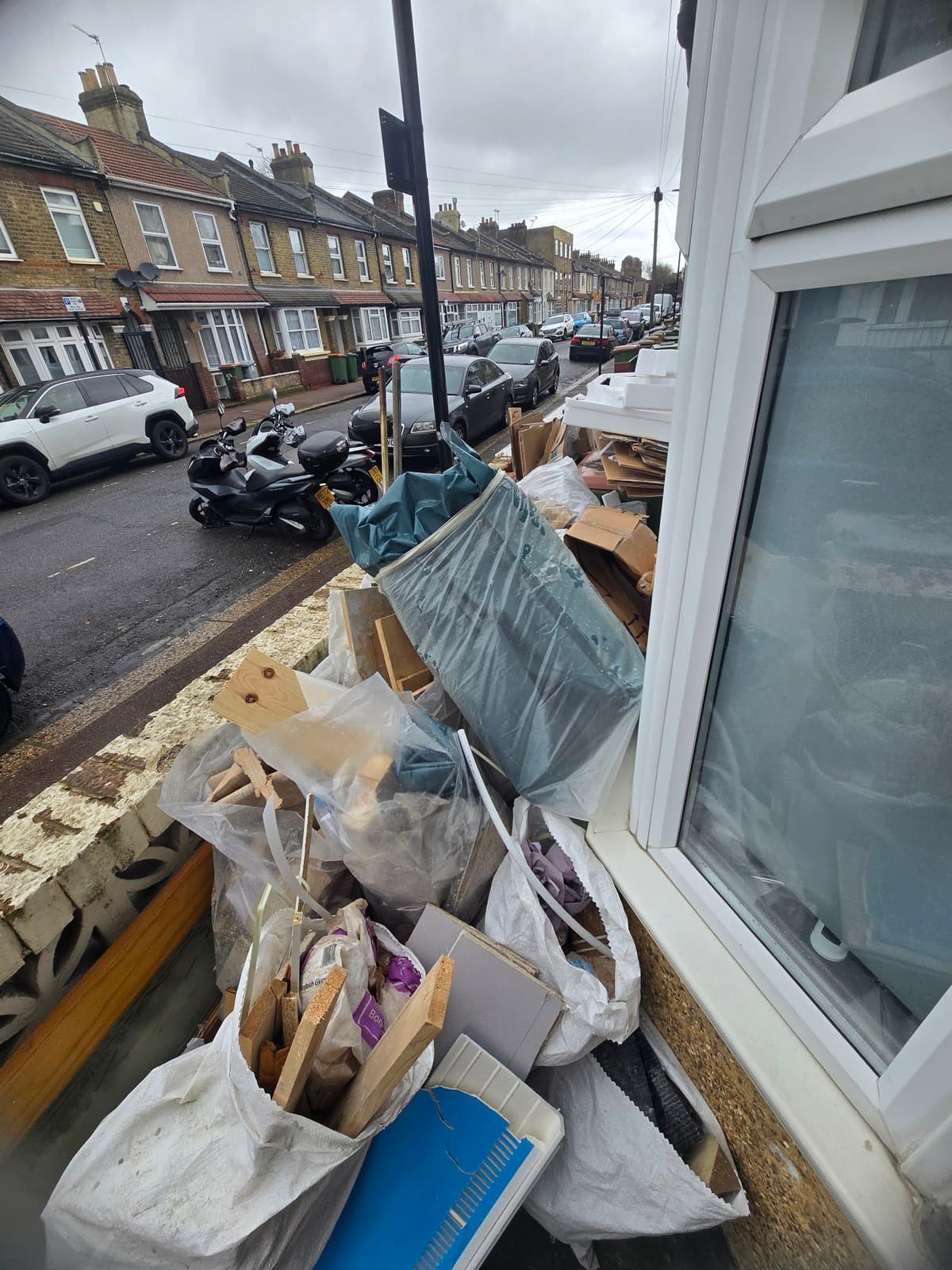 Bulk bags of builders’ waste, timber offcuts and packaging waiting for collection outside a terraced house